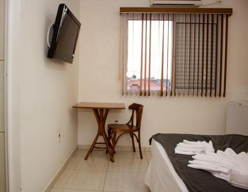a room with a bed and a table and a television at Hotel Garrafão - Rua Principal de Boituva in Boituva