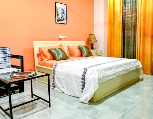 a bedroom with a bed with orange walls and a table at Villa Soudan in Bobo-Dioulasso