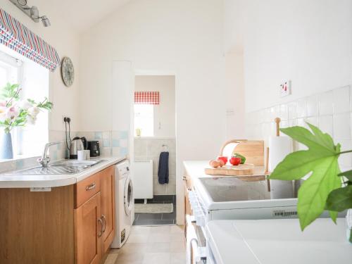 a white kitchen with a sink and a dishwasher at Windygates in Rhosneigr