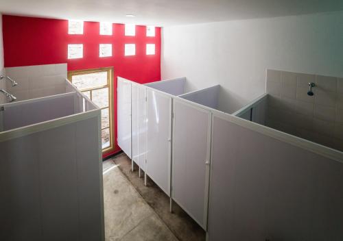 a bathroom with white cabinets and a red wall at Imagine hostel in Santa Marta