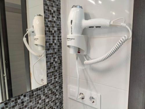 a white phone hanging on a wall in a bathroom at Hostal Óleo Auto Check-in in Santander