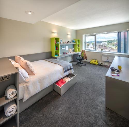 een slaapkamer met een bed, een bureau en een raam bij Victoria Mills Apartments - UCC Summer Beds in Cork