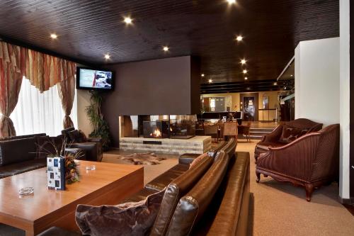 a living room with leather furniture and a tv at Snezhanka Hotel Pamporovo - All inclusive in Pamporovo