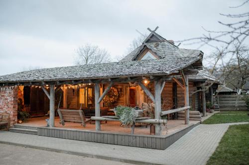 uma cabana de madeira com um alpendre e um banco em Raxti em Kuldīga