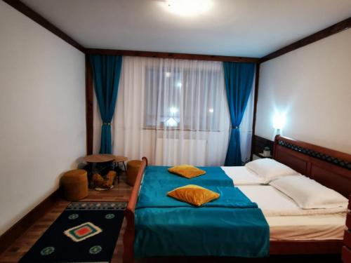 a bedroom with a bed with blue sheets and a window at Vila Romanitza in Dărmăneşti