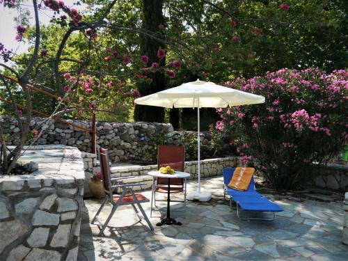 a patio with a table and an umbrella and chairs at Blumenhaus (Spiti Louloudia) in Paralía Sergoúlas