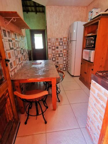 a kitchen with a wooden table and a refrigerator at Chalés Ki Aconchego -Condominio Morada da Praia - Boracéia in Boracéia
