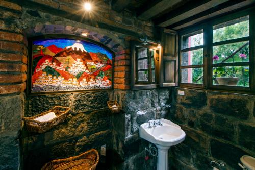 baño de piedra con lavabo y TV en la pared en Hacienda Hato Verde en Mulaló