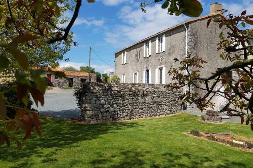 una vecchia casa in pietra con un muro di pietra di La Commanderie Grand Gite 10kms " Puy duFou" a Mauléon