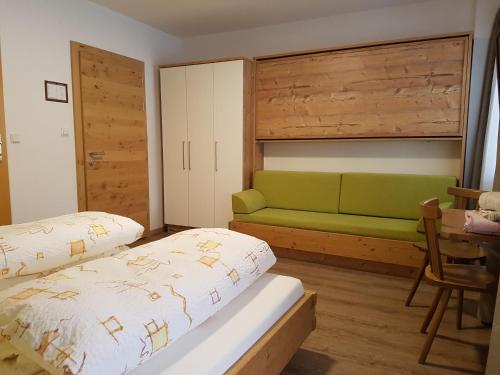 a bedroom with a bed and a green couch at Unterbergerhof in Val di Vizze