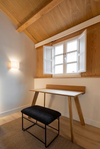 a table and a stool in a room with a window at NORO Plaza in A Coruña