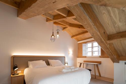 a bedroom with a large white bed with wooden ceilings at NORO Plaza in A Coruña