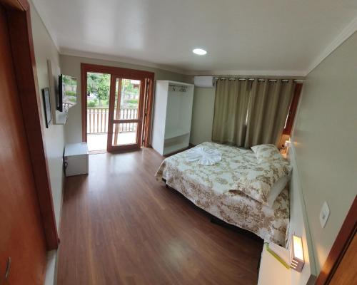 1 dormitorio con 1 cama y suelo de madera en Hotel Pousada Cabana da Mata, en Gramado