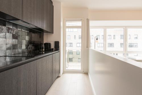 una cocina con armarios de madera y una gran ventana en Vitamin Sea, in het centrum en naast de zee, en Ostende