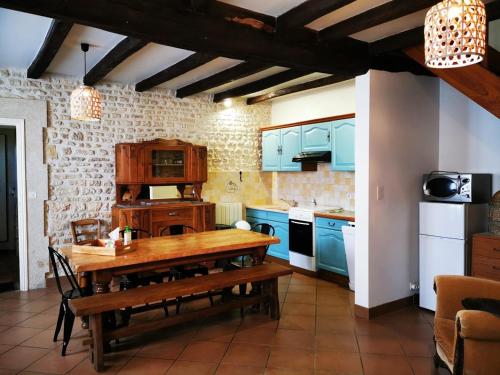 cocina con mesa de madera y armarios azules en Gîte Le Bonheur en Hiersac