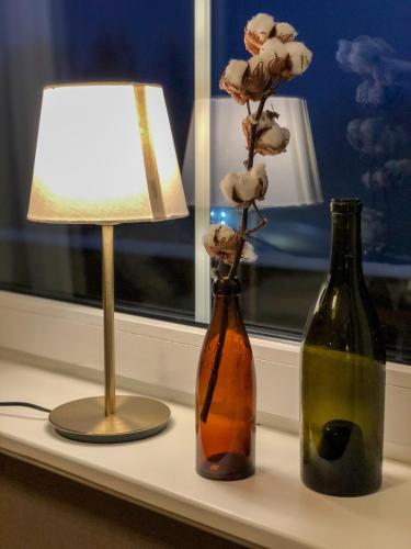 two bottles on a window sill with a lamp and flowers at Villa Bergli in Malung