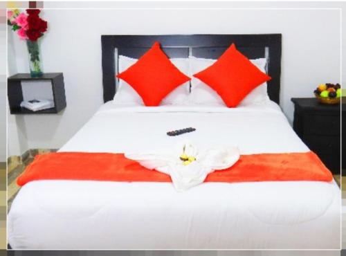 a bed with red pillows and a white flower on it at Hotel Casa Román in Bogotá