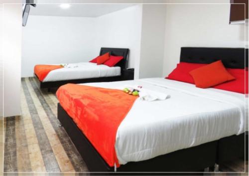 2 camas en una habitación con almohadas rojas. en Hotel Casa Román en Bogotá