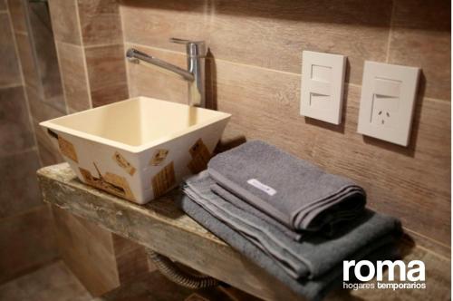 baño con lavabo y toallas en la encimera en ROMA Hogares Temporarios en Villa María