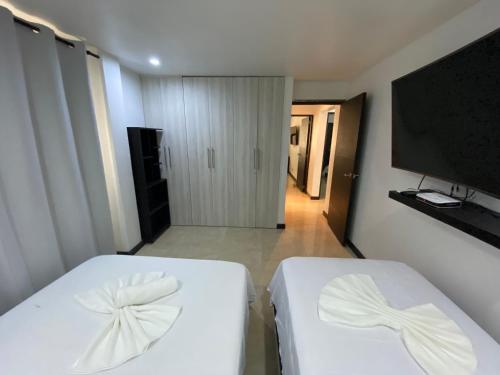 a bedroom with two white beds and a flat screen tv at Apartamentos Martinez in San Andrés