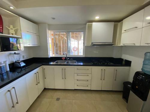a kitchen with white cabinets and black counter tops at Apartamentos Martinez in San Andrés