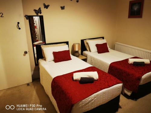 a bedroom with two beds with red and white sheets at oddfellowsbandb in Blythe