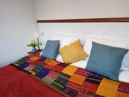 uma cama com um cobertor colorido e almofadas em The Sett on The Wharfe em Threshfield