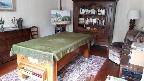 una sala de estar con una mesa con una cubierta verde en Le Verger de Mathurin, en Le Molay-Littry