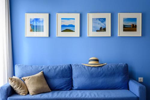 a blue couch against a blue wall with four pictures at Elounda Colour Apartments in Elounda