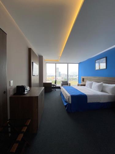 a hotel room with a bed and a large window at Wyndham Puebla Angelopolis in Puebla