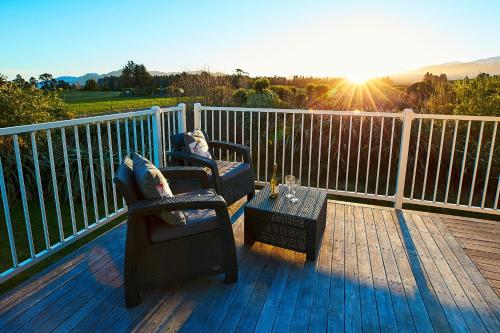 two chairs and a table on a deck with the sun at Kakatu Retreat Bed & Breakfast in Kaikoura
