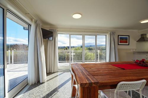 a dining room with a wooden table and a balcony at Kakatu Retreat Bed & Breakfast in Kaikoura