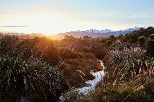 a river in a field with mountains in the background at Kakatu Retreat Bed & Breakfast in Kaikoura