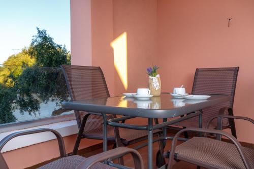 a table and chairs on a balcony with a window at Georgioupoli Studios in Georgioupolis