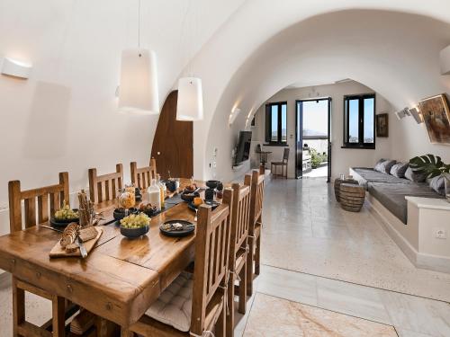 a dining room and living room with a wooden table at Luxury Villa Blue Dome Santorini in Imerovigli