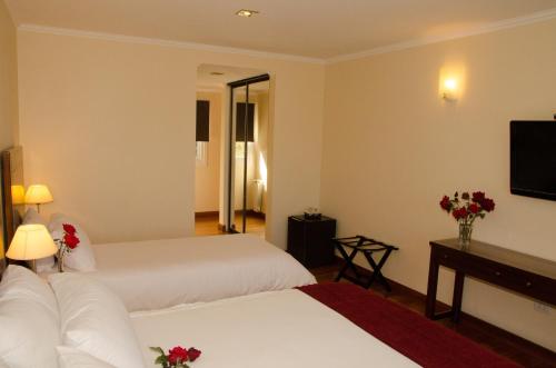 a hotel room with two beds and a television at Alma Andina Hosteria in Villa La Angostura