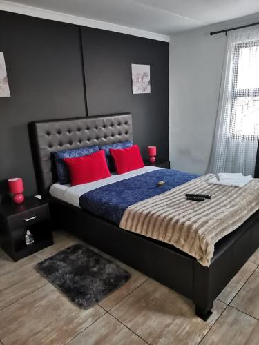 1 dormitorio con 1 cama grande con almohadas rojas en ILITHA PARK, en Ciudad del Cabo