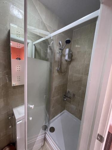 a bathroom with a shower with a glass door at Modern Garden House in Harrow