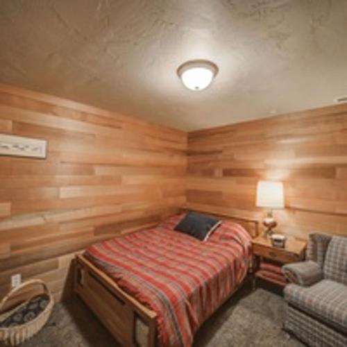 a bedroom with wooden walls and a bed and a chair at Cascade Log Cabin by Casago McCall - Donerightmanagement in Cascade