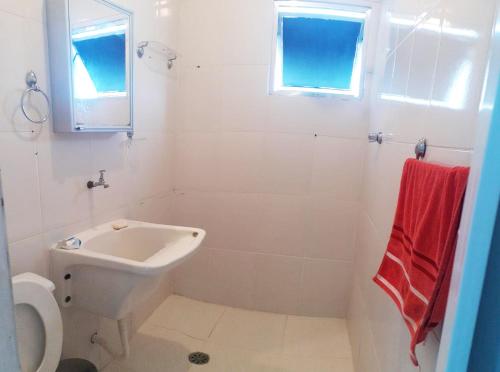 a white bathroom with a sink and a toilet at Residencial Alemão in Guarujá