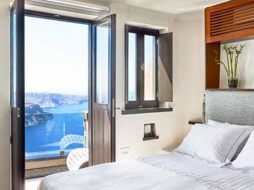 a bedroom with a bed and a view of the water at Luxury Villa Blue Dome Santorini in Imerovigli