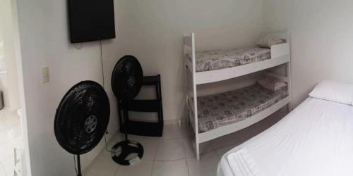 a room with two beds and a chair and a television at Residencial Alemão in Guarujá