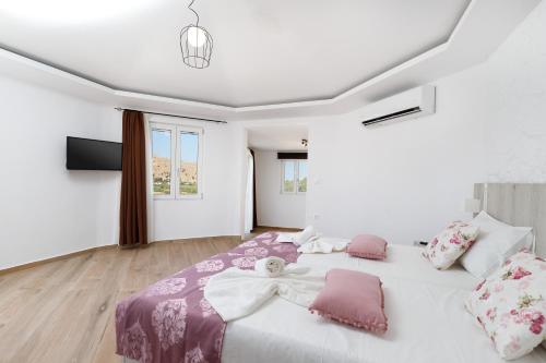 una camera bianca con un grande letto con cuscini rosa di Georgioupoli Studios a Georgioupolis