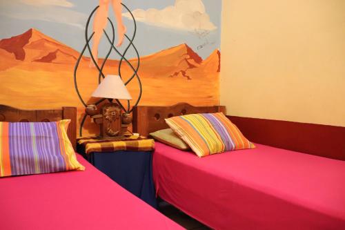 two beds in a room with a painting on the wall at Hostel Casa Zalaoui in Guadalajara