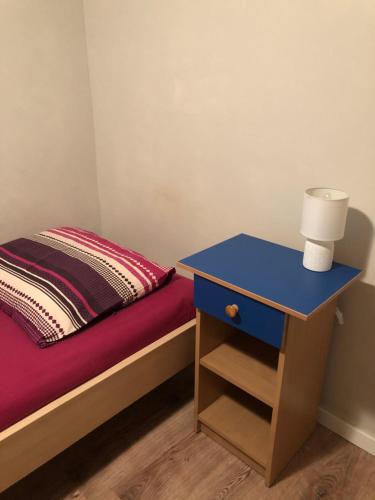 a bed with a blue night stand next to a blue bed at Tanie Pokoje Blisko Lotniska in Poznań