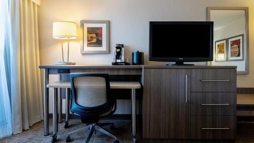 a desk with a television and a chair in a hotel room at Holiday Inn Nashville - Vanderbilt - Dwtn by IHG in Nashville