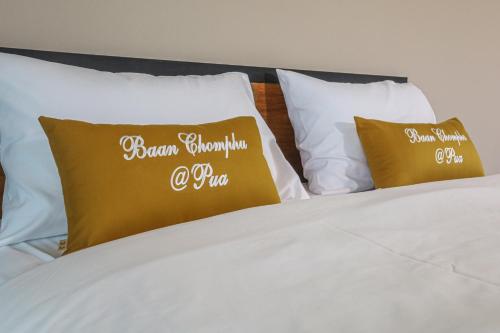 a bed with white sheets and gold pillows at Baan chomphu @Pua in Pua