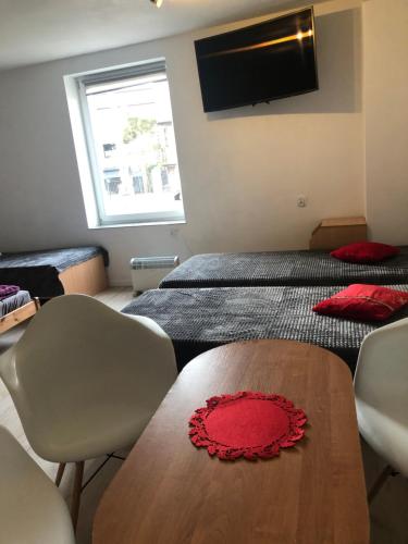 a room with two beds and a table with a red flower on it at Tanie Pokoje Blisko Lotniska in Poznań