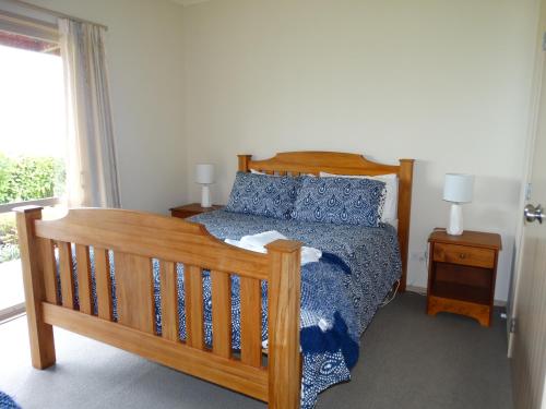 1 dormitorio con cama de madera y ventana en Kauri Lodge Karapiro en Karapiro