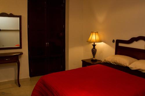 a bedroom with a red bed with a lamp and a mirror at Cuartel 1914 - Hotel Boutique in Zacatecas